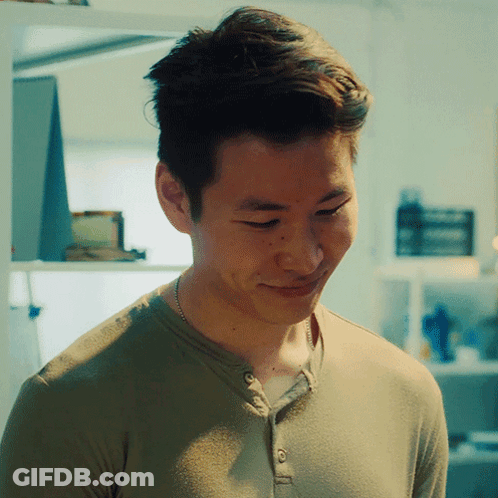 A Man Wearing A Green Shirt And A Necklace Smiles GIF