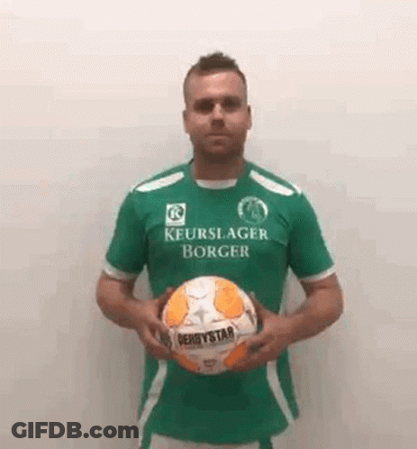 A Man Wearing A Green Shirt Is Holding A Soccer Ball . GIF