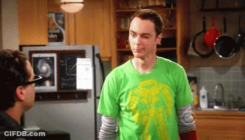 A Man Wearing A Green Shirt Is Standing In A Kitchen Next To A Refrigerator . GIF