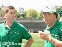 A Man Wearing A Green Shirt That Says ' Ucsd ' On It Stands Next To Another Man GIF