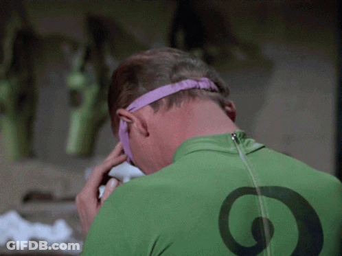 A Man Wearing A Green Shirt With A Black Circle On The Back Is Talking On A Cell Phone GIF
