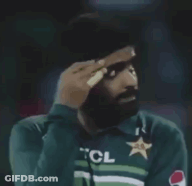 A Man Wearing A Green Shirt With A Star On It Is Covering His Face With His Hand . GIF