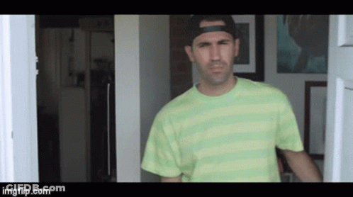 A Man Wearing A Green Striped Shirt And A Black Hat Is Standing In A Doorway .. GIF