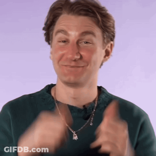 A Man Wearing A Green Sweater And A Necklace Is Clapping GIF