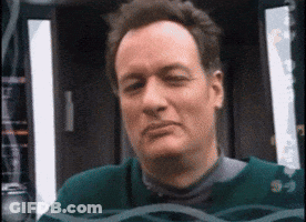 A Man Wearing A Green Sweater Is Looking At The Camera With His Eyes Closed GIF