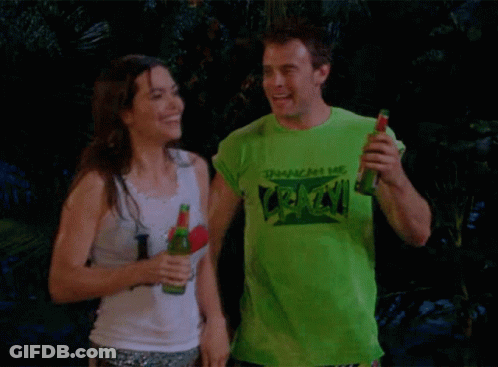 A Man Wearing A Green T-Shirt That Says " Crack " Holds A Bottle Of Beer Next To A Woman GIF