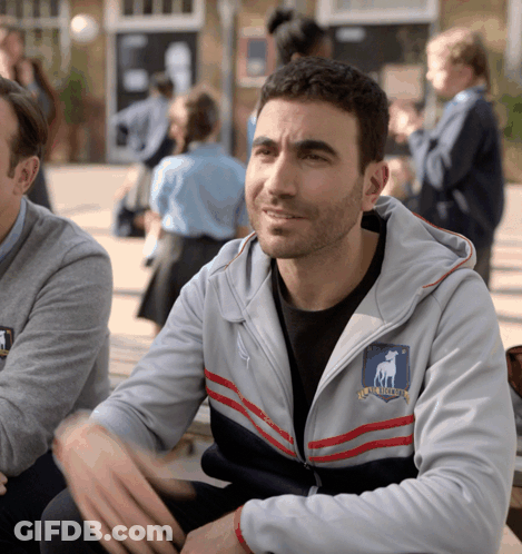 A Man Wearing A Grey Jacket With A Shield That Says Rugby League On It GIF