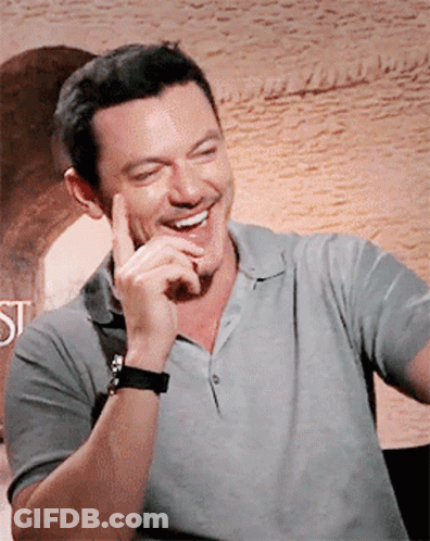 A Man Wearing A Grey Shirt And A Black Watch Is Smiling GIF
