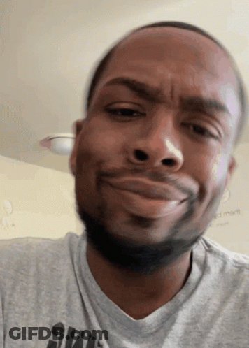 A Man Wearing A Grey Shirt With The Word Smart On It Looks At The Camera GIF