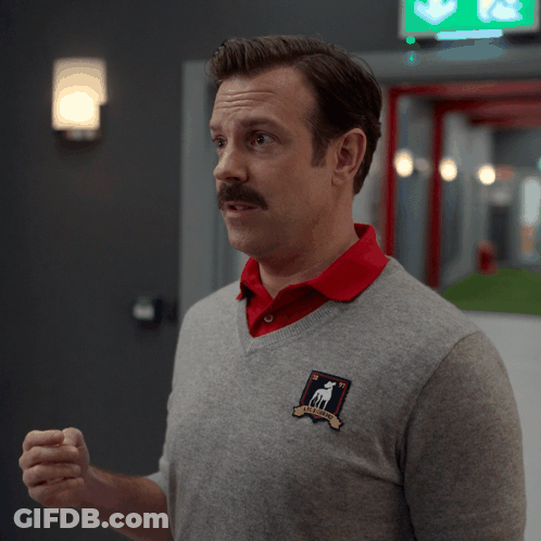 A Man Wearing A Grey Sweater And A Red Shirt Has The Word Yuck On His Shirt GIF