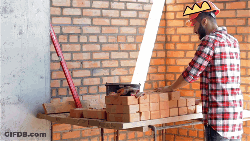 A Man Wearing A Hard Hat And A Crown Is Working On Bricks GIF