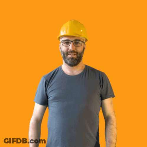 A Man Wearing A Hard Hat And Glasses Holds His Fist Up In The Air GIF