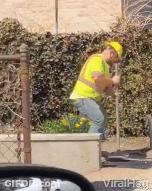 A Man Wearing A Hard Hat And Safety Vest Is Digging In The Ground GIF