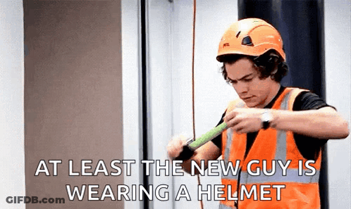 A Man Wearing A Hard Hat And Safety Vest Is Holding A Tape Measure . GIF