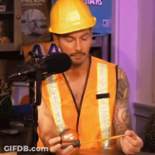 A Man Wearing A Hard Hat And Safety Vest Is Measuring Something With A Tape Measure GIF