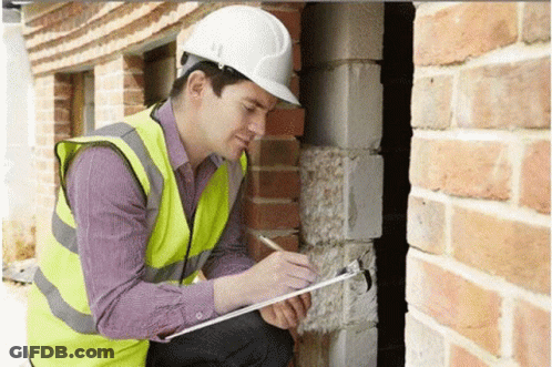 A Man Wearing A Hard Hat Is Writing On A Clipboard . GIF