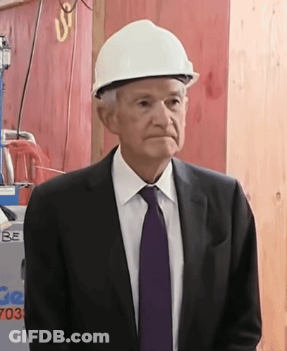 A Man Wearing A Hard Hat Stands In Front Of A Sign That Says Be GIF