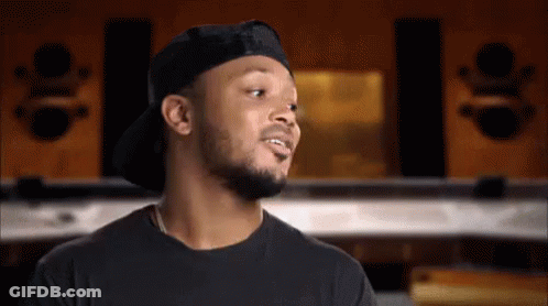 A Man Wearing A Hat And A Black Shirt Is Talking To Someone GIF