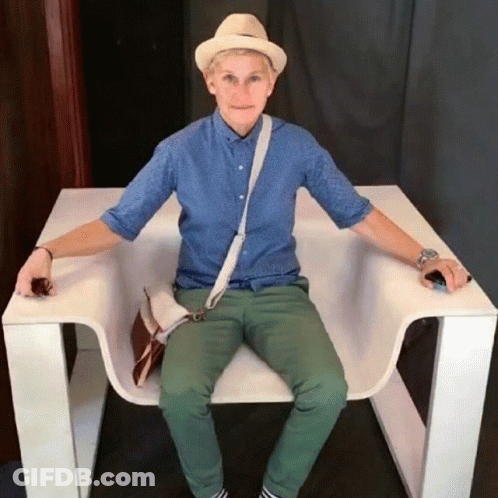 A Man Wearing A Hat And A Blue Shirt Is Sitting In A White Chair GIF