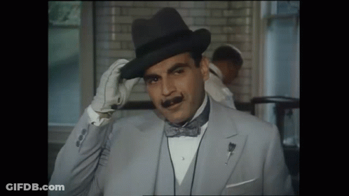 A Man Wearing A Hat And A Bow Tie Adjusts His Hat GIF