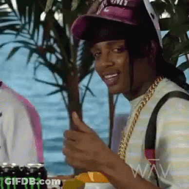 A Man Wearing A Hat And A Chain Is Giving A Thumbs Up Sign . GIF
