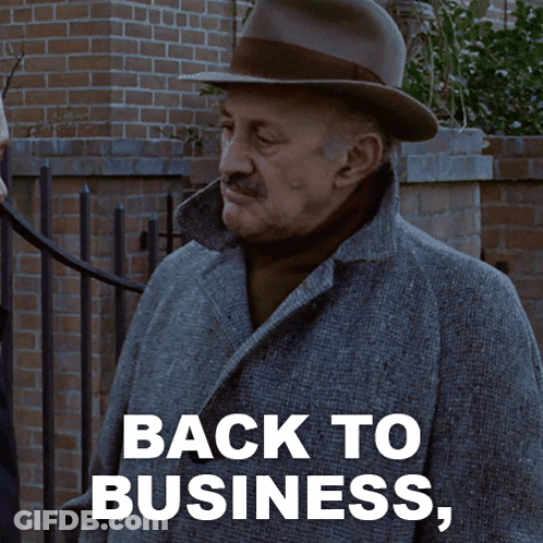 A Man Wearing A Hat And A Coat Says " Back To Business " GIF