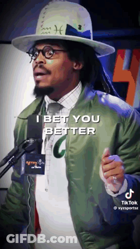 A Man Wearing A Hat And A Green Jacket Stands In Front Of A Microphone And Says I Bet You Better GIF