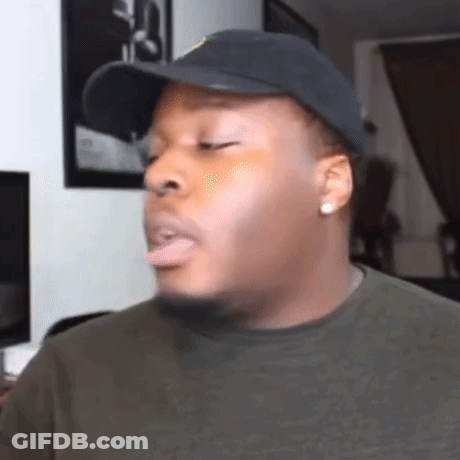 A Man Wearing A Hat And A Green Shirt Is Making A Funny Face In A Living Room . GIF