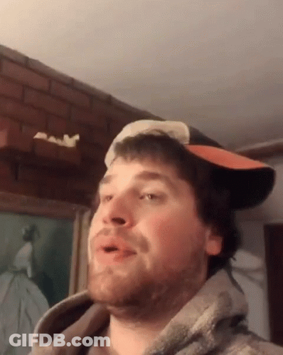 A Man Wearing A Hat And A Hoodie Is Making A Face GIF