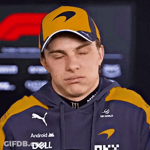 A Man Wearing A Hat And A Hoodie Is Making A Funny Face With His Eyes Closed . GIF