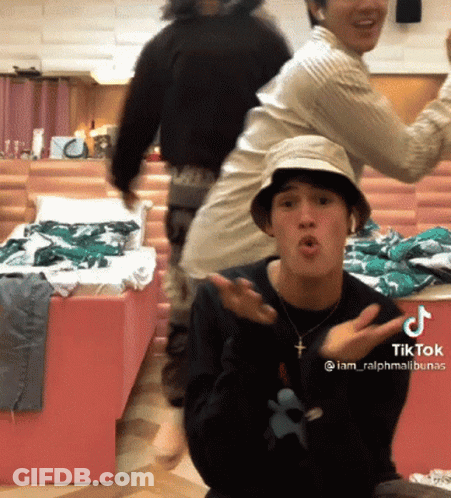 A Man Wearing A Hat And A Necklace With A Cross On It Has A Tiktok Sticker On His Chest GIF