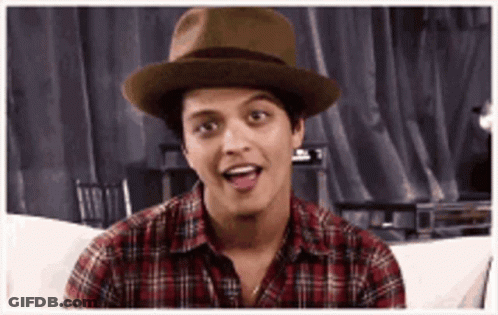 A Man Wearing A Hat And A Plaid Shirt Is Sitting On A Couch And Making A Funny Face . GIF