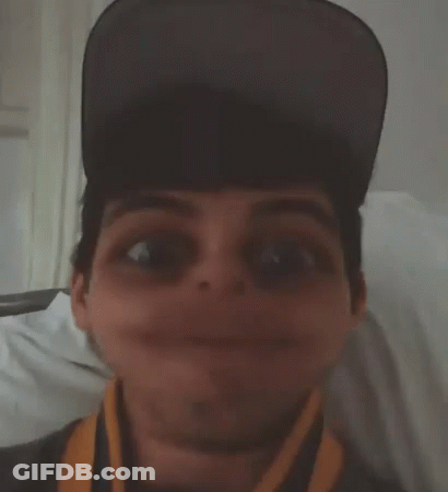 A Man Wearing A Hat And A Scarf Makes A Funny Face GIF