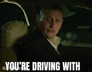 A Man Wearing A Hat And A Suit Is Driving A Car GIF