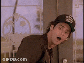 A Man Wearing A Hat And A Suit Is Standing In Front Of A Door With His Mouth Open . GIF