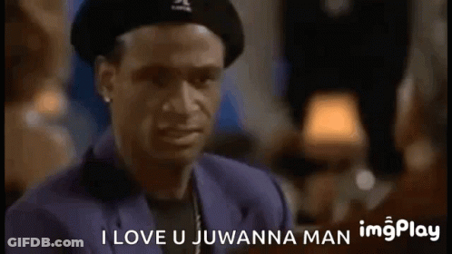 A Man Wearing A Hat And A Suit Is Talking To Another Man In A Bar . GIF