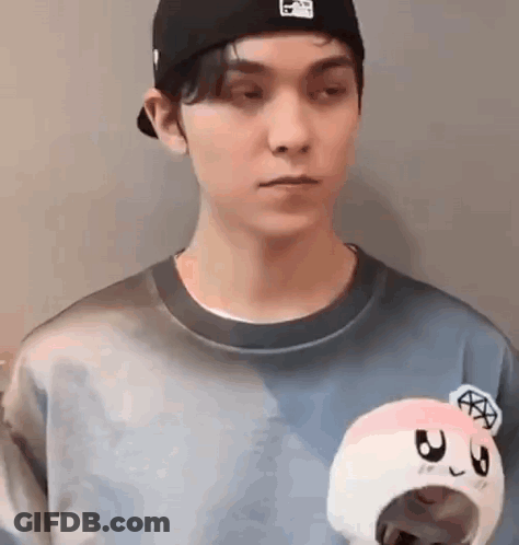 A Man Wearing A Hat And A Sweater Is Holding A Stuffed Animal . GIF