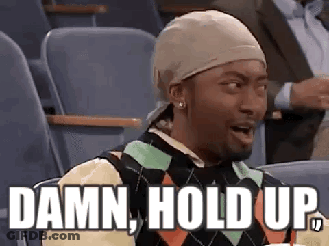 A Man Wearing A Hat And A Sweater Is Sitting In A Stadium With The Words `` Damn , Hold Up '' . GIF