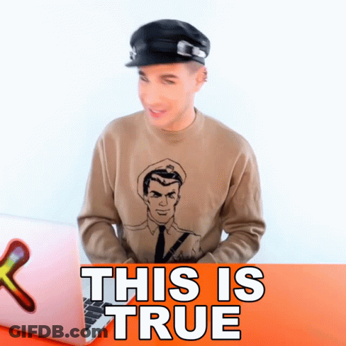 A Man Wearing A Hat And A Sweater That Says This Is True Sits In Front Of A Laptop GIF