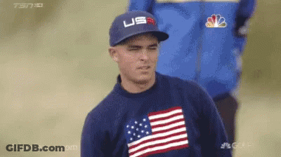 A Man Wearing A Hat And A Sweater With An American Flag On It GIF