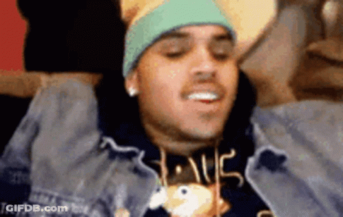 A Man Wearing A Hat And A Sweatshirt With The Word Love On It Is Laying On A Couch . GIF