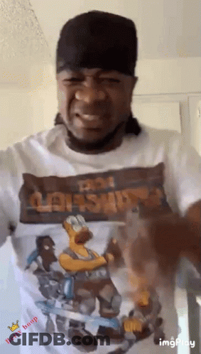 A Man Wearing A Hat And A T-Shirt With A Picture Of Homer Simpson On It . GIF