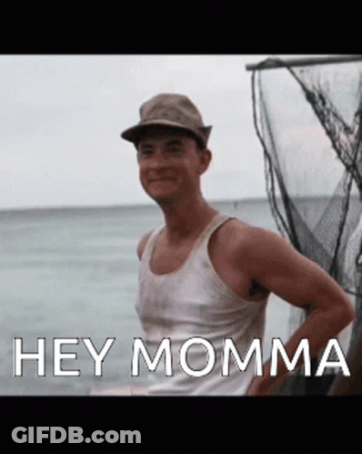 A Man Wearing A Hat And A Tank Top Is Standing In Front Of A Body Of Water And Says Hey Momma GIF
