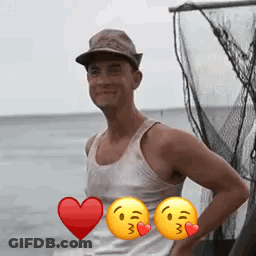 A Man Wearing A Hat And A Tank Top Is Standing In Front Of A Fishing Net With Two Smiley Faces . GIF