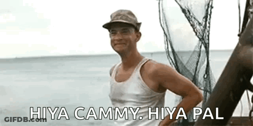 A Man Wearing A Hat And A Tank Top Is Standing On A Boat In The Water . GIF