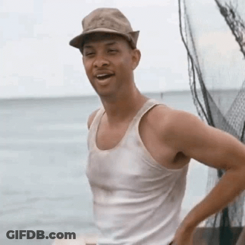 A Man Wearing A Hat And A Tank Top Is Standing On A Boat Near The Ocean . GIF