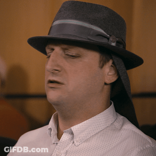 A Man Wearing A Hat And A White Shirt Looks Tired GIF