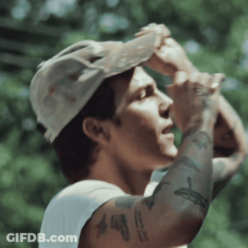A Man Wearing A Hat And A White Tank Top Has A Tattoo On His Arm That Says ' I Love You ' GIF