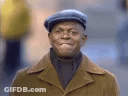 A Man Wearing A Hat And Coat Is Smiling . GIF