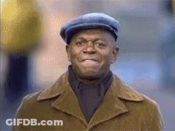 A Man Wearing A Hat And Coat Is Smiling . GIF